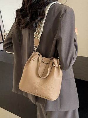 Textured crossbody bag in Khakis with a unique patterned strap and drawstring closure.