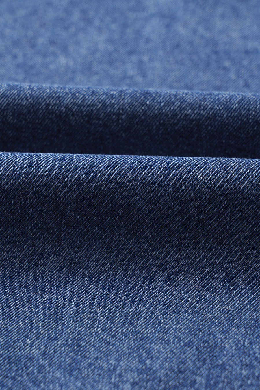 Utility denim mini dress in medium blue, showing fabric texture and folds.