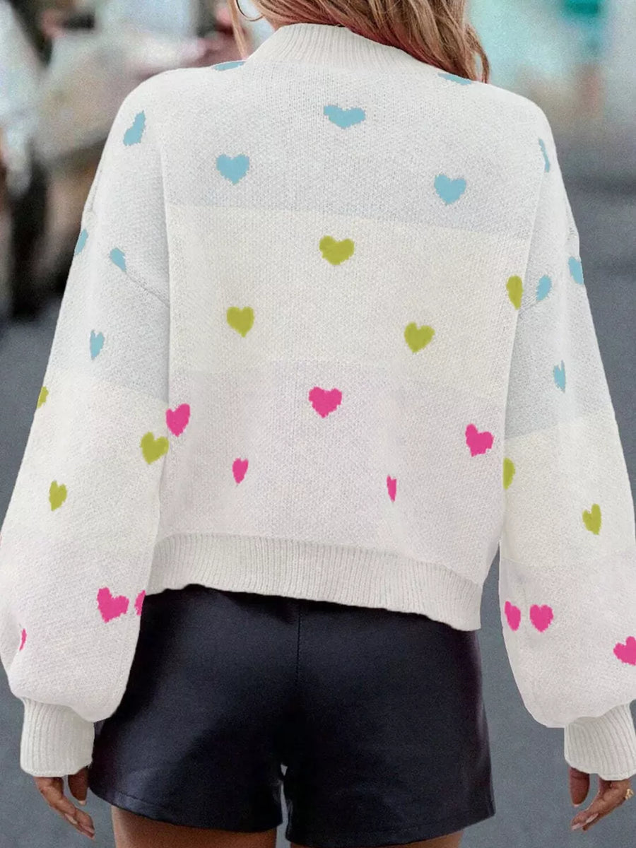 White knit sweater with colorful heart pattern, crew neck, and balloon sleeves.