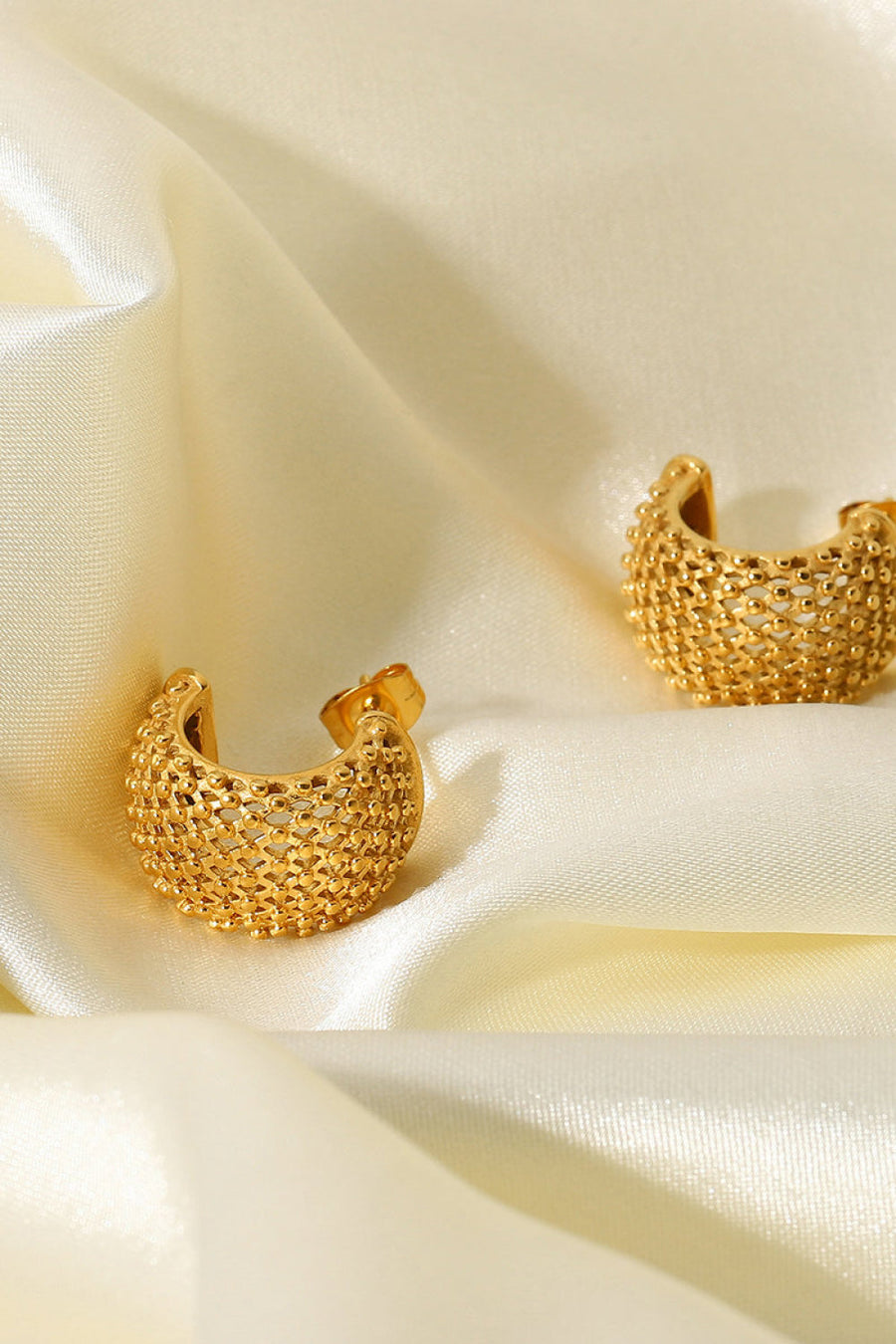 Textured gold crescent earrings with a beaded pattern.