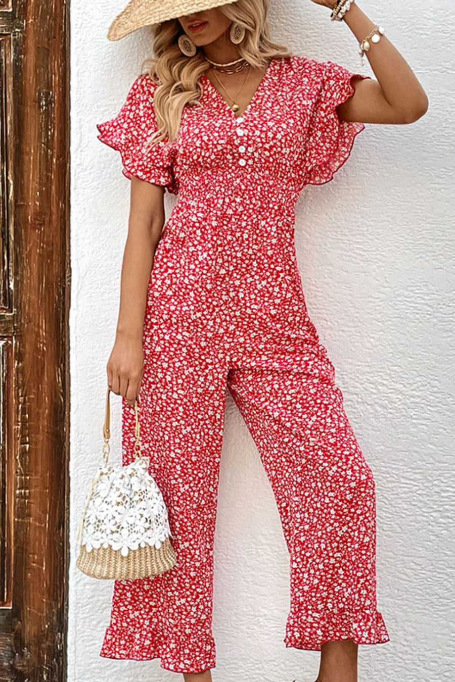 Floral smocked bodice jumpsuit with flutter sleeves and decorative buttons.