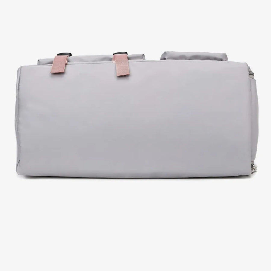 Gray duffel bag with pink buckle straps and top handles.