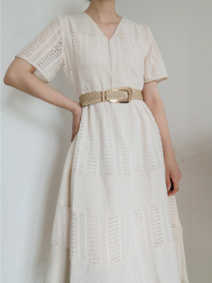 Woven raffia belt with gold-tone buckle, cinching a white lace dress.