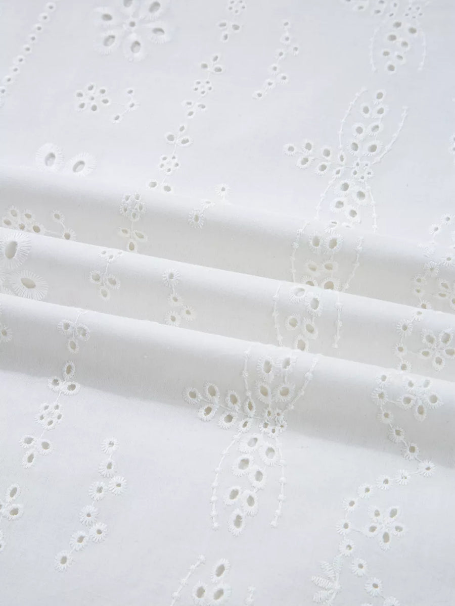 White cotton blouse with delicate eyelet embroidery and ruffled details.