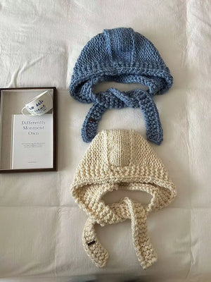 Blue and off-white chunky knit wool earflap beanies with ties.