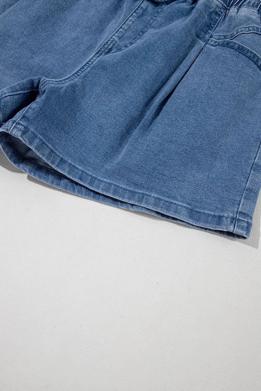Medium wash denim shorts with paperbag waist and relaxed fit.