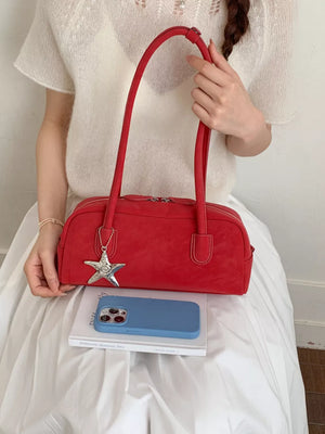 Red shoulder bag with star charm and double zipper closure.