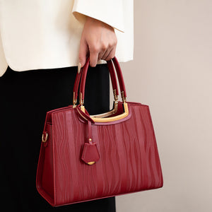 Red embossed tote handbag with gold hardware and top handles.