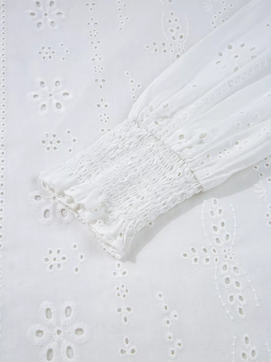 White cotton blouse with eyelet embroidery and smocked cuff detail.