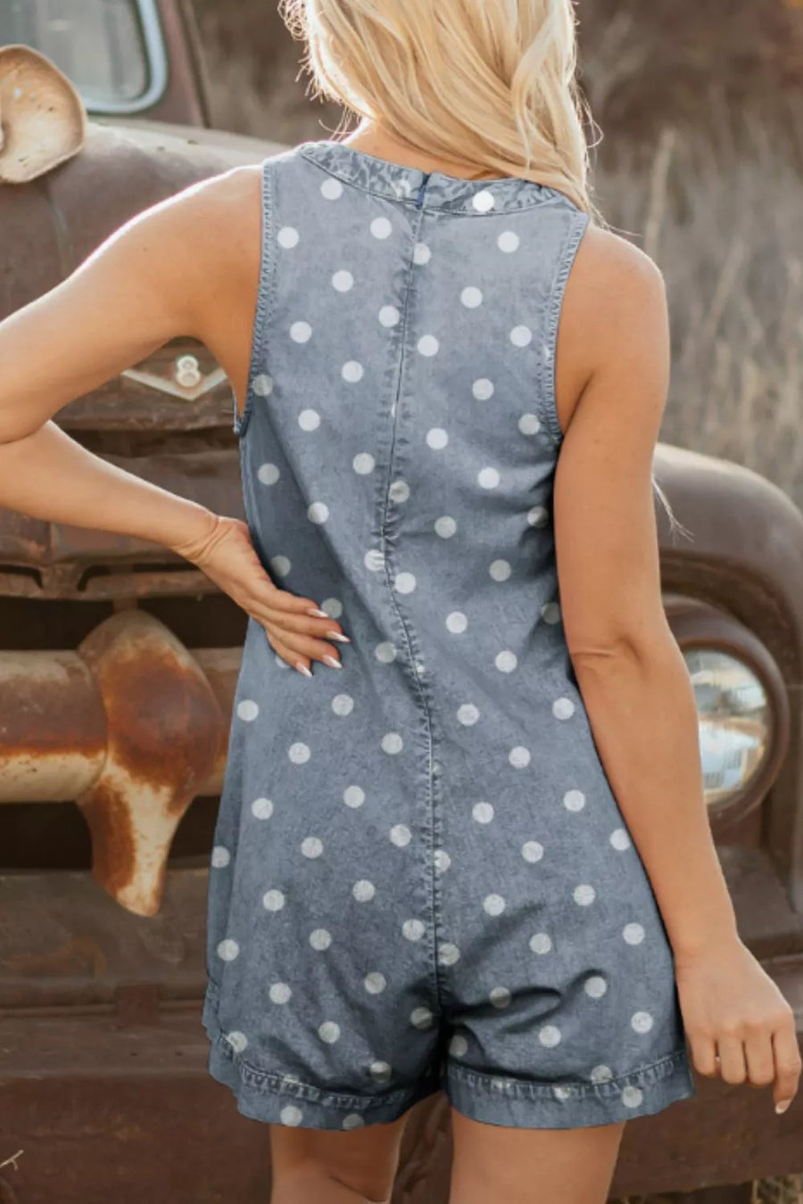 Denim polka dot romper with tie-front detail, sleeveless, and collared neckline.