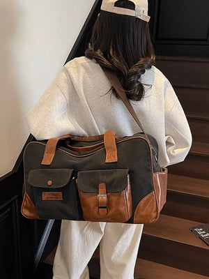 Black canvas travel bag with brown leather accents and multiple front pockets.