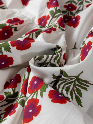 V-neck mini dress in white cotton with a red and purple floral print and green leaves.