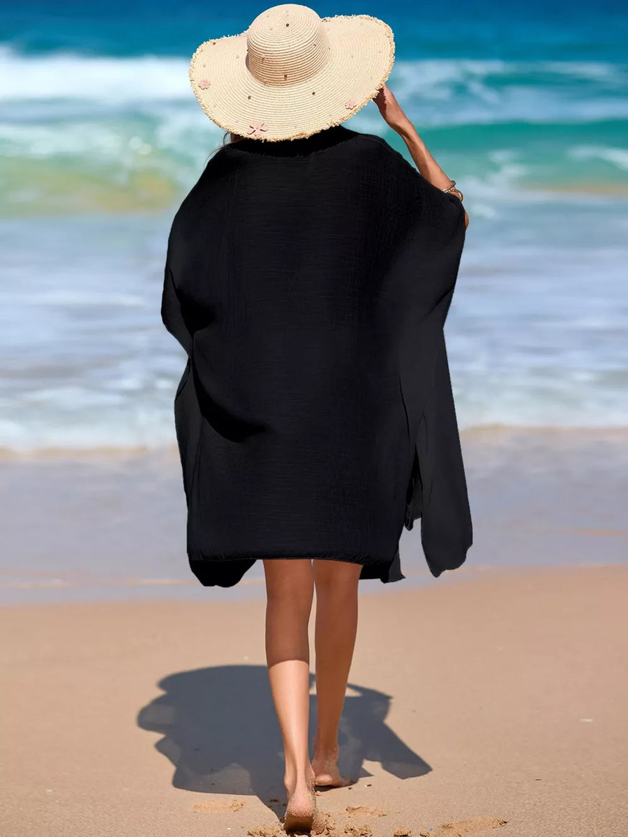 Black button-up cover-up with short sleeves and a relaxed fit, worn on a beach.
