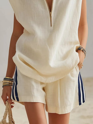 Cream linen shorts with navy side stripes and a matching sleeveless zip-neck top.