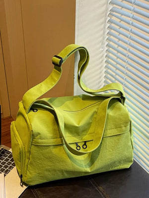 Green nylon duffel bag with adjustable strap and two front zipper pockets.