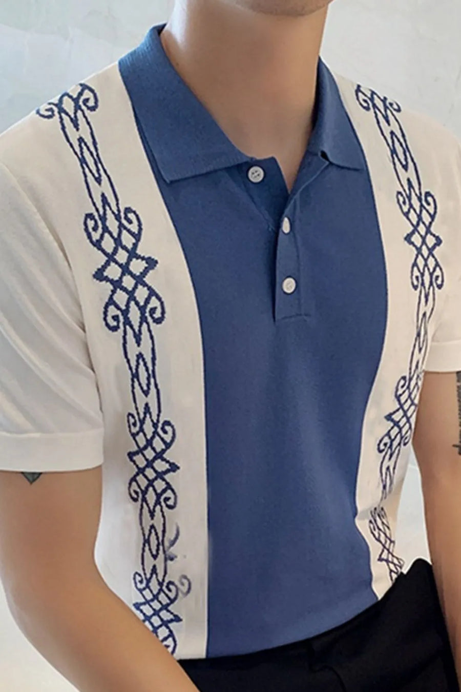 Embroidered panel polo shirt in dusty blue and white with ornate blue stitching details.