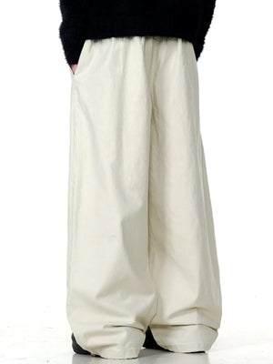Relaxed wide-leg trousers in light beige with drawstring waist and pockets.