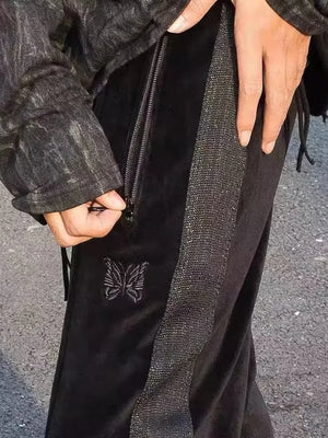 Black velour sweatpants with butterfly emblem and sparkly side stripe.