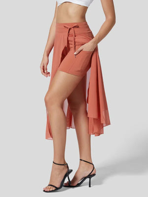 Flowy midi skirt with shorts liner in orange red, featuring a drawstring waist and pockets.