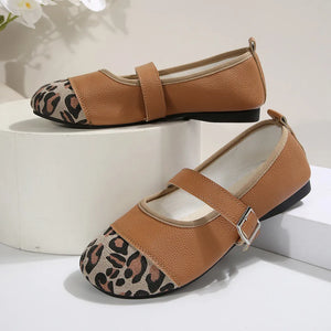 Brown cap-toe Mary Jane flats with leopard print accent and buckle strap.