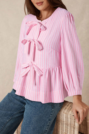 Blush pink striped peplum blouse with bow details and long sleeves.