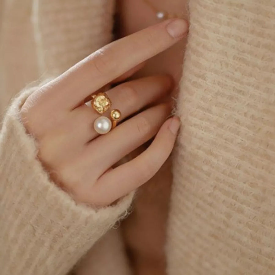 Lustrous pearl and gold open ring with textured detail.