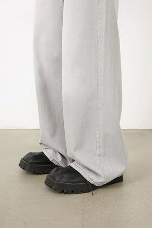 Bleached wash wide-leg denim trousers in gray, styled with chunky black boots.