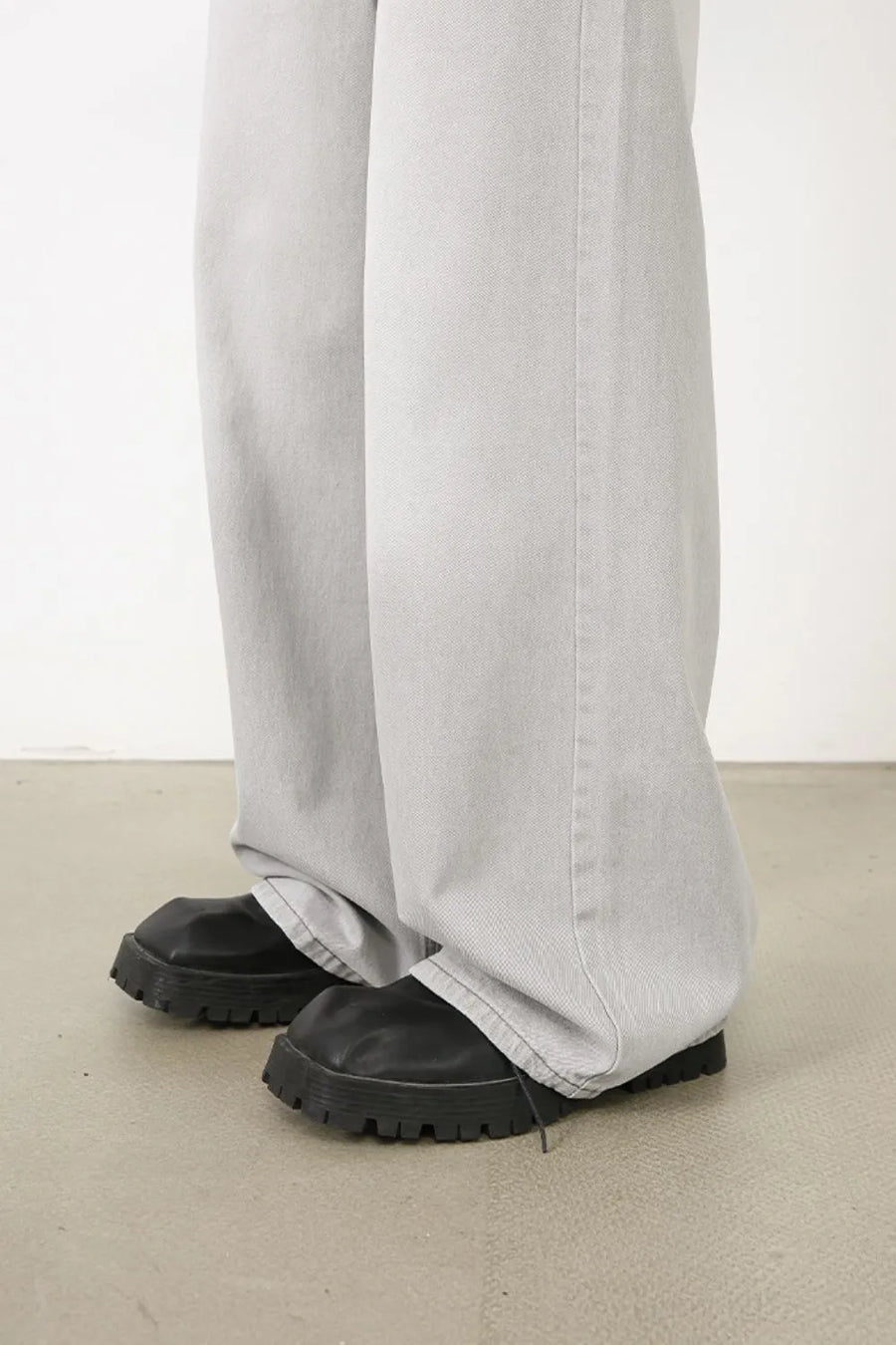 Bleached wash wide-leg denim trousers in gray, styled with chunky black boots.