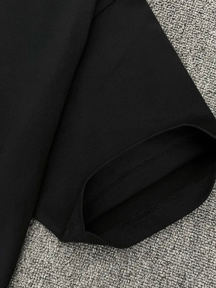 Black oversized crew neck tee with visible stitching detail on hem and sleeve.