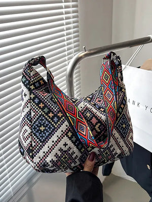 Embroidered geometric hobo bag with colorful strap.