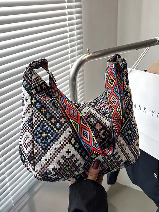 Embroidered geometric hobo bag with colorful strap.