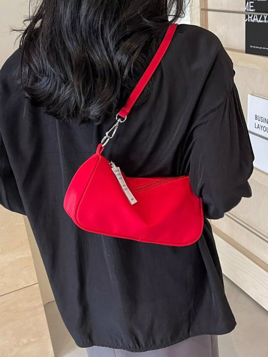 Red nylon mini crossbody bag with silver zipper detail and adjustable strap.