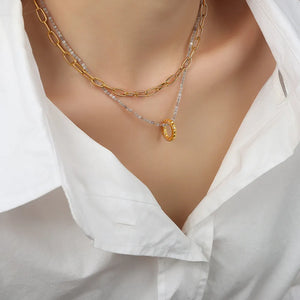 Gold layered chain necklace with beaded strand and textured ring pendant.