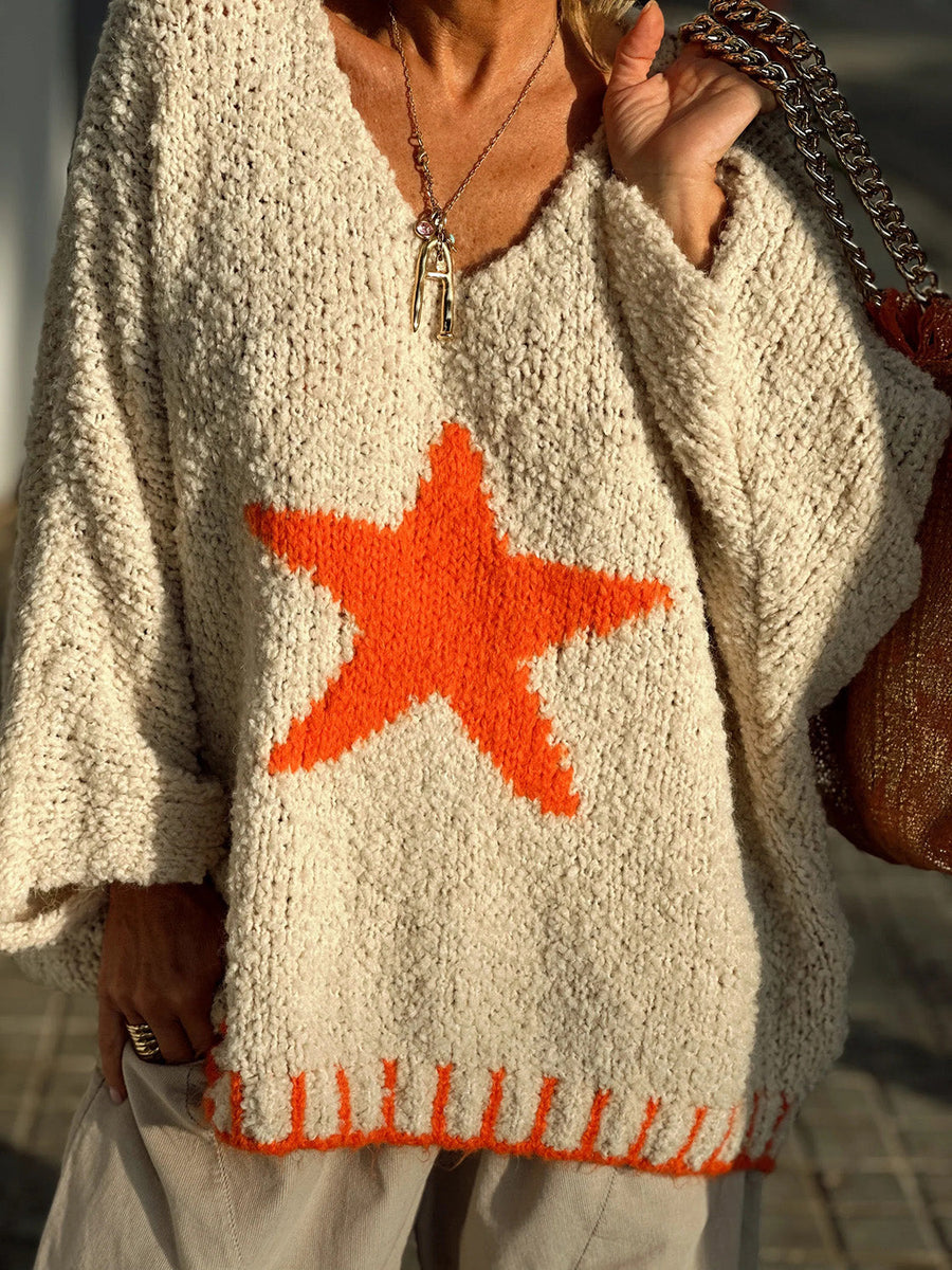 Cream knit v-neck pullover with orange star and striped hem detail.