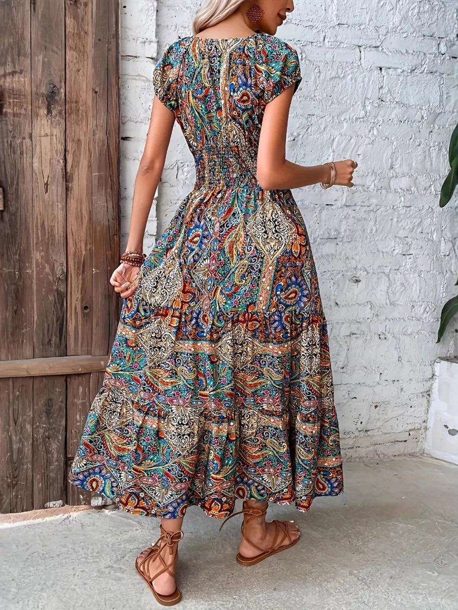 Vibrant tiered maxi dress with smocked bodice and colorful paisley print.