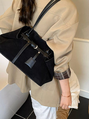 Black suede shoulder bag with leather trim and buckle detail.