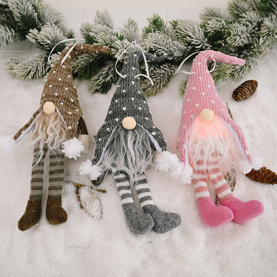 Knitted gnome ornaments in light gray, blush pink, and khaki with striped legs and pom-pom accents.