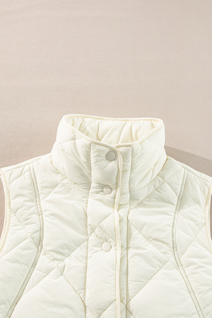 Ivory quilted stand collar vest with snap front closure and diamond pattern.