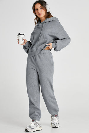 Gray relaxed fit loungewear set with hoodie and jogger pants, featuring pockets and adjustable drawstring.