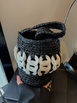 Black woven straw bucket tote with white ring detail and braided handle.