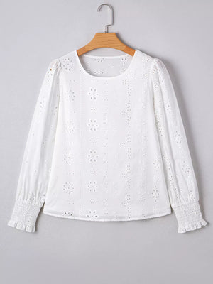 White cotton blouse with eyelet embroidery, ruffled cuffs, and puff sleeves.