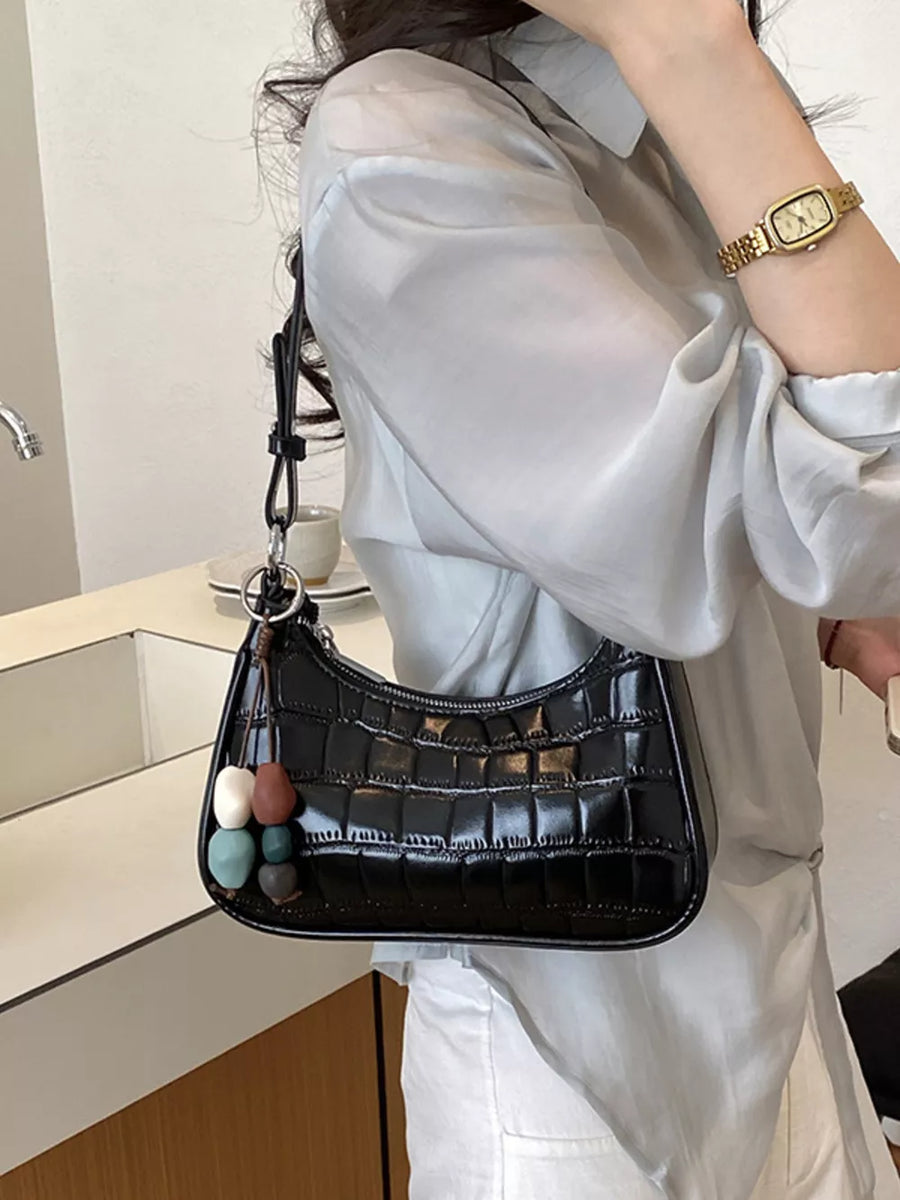 Black shoulder bag featuring textured and crocodile-embossed