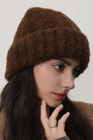 Textured bouclé knit beanie in chocolate brown, styled casually.