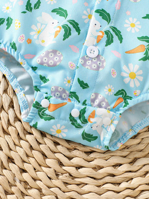 Baby bodysuit with bunny, carrot, and flower print on blue fabric, featuring white buttons.