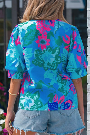 Vibrant floral v-neck blouse with relaxed fit and short puff sleeves, styled with denim shorts.