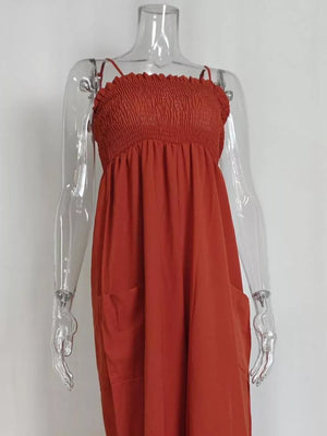 Orange-red smocked wide leg romper with spaghetti straps and side pockets.