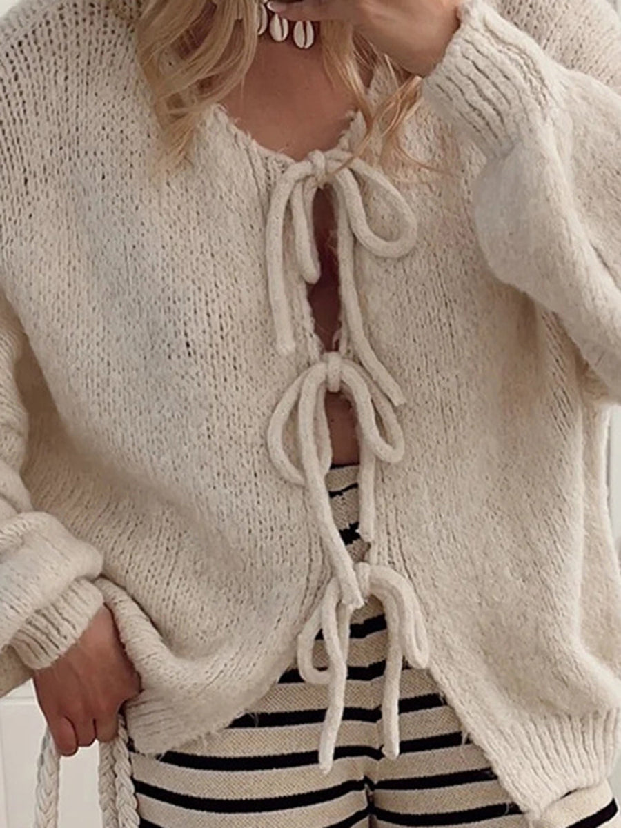 Beige knit cardigan with balloon sleeves and lace-up front detail.