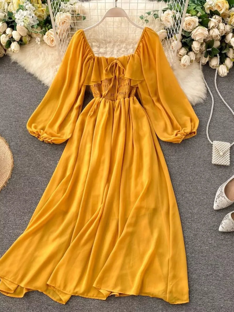Yellow maternity dress with square neck, ruffled detail, smocked bodice, balloon sleeves, and A-line skirt.