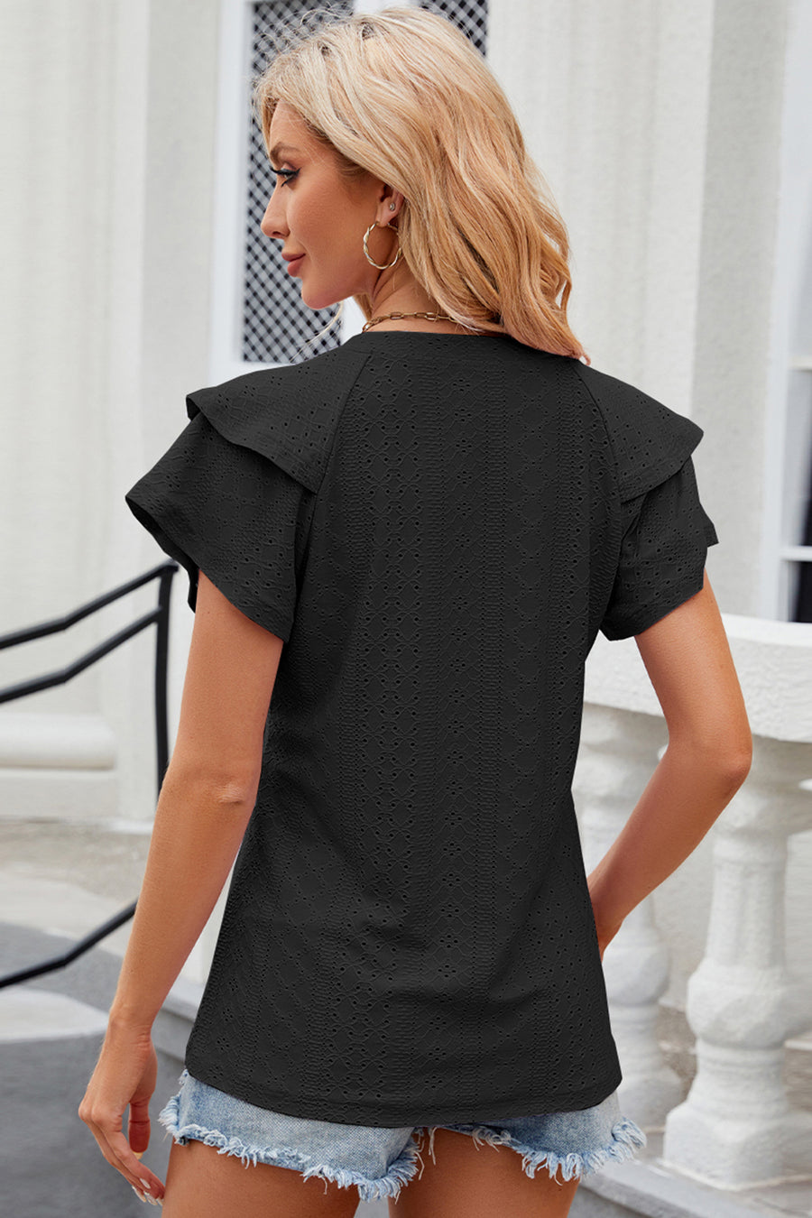 Black eyelet blouse with flutter sleeves and textured fabric.