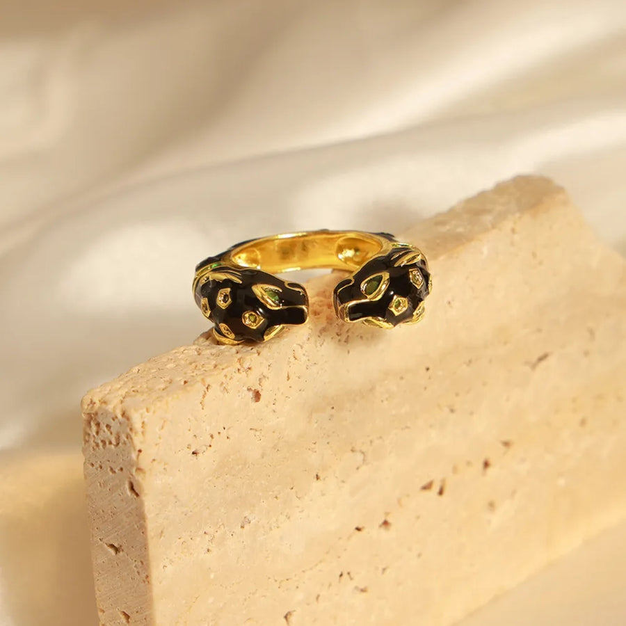 Gold open ring with black enamel panther heads and green gem eyes